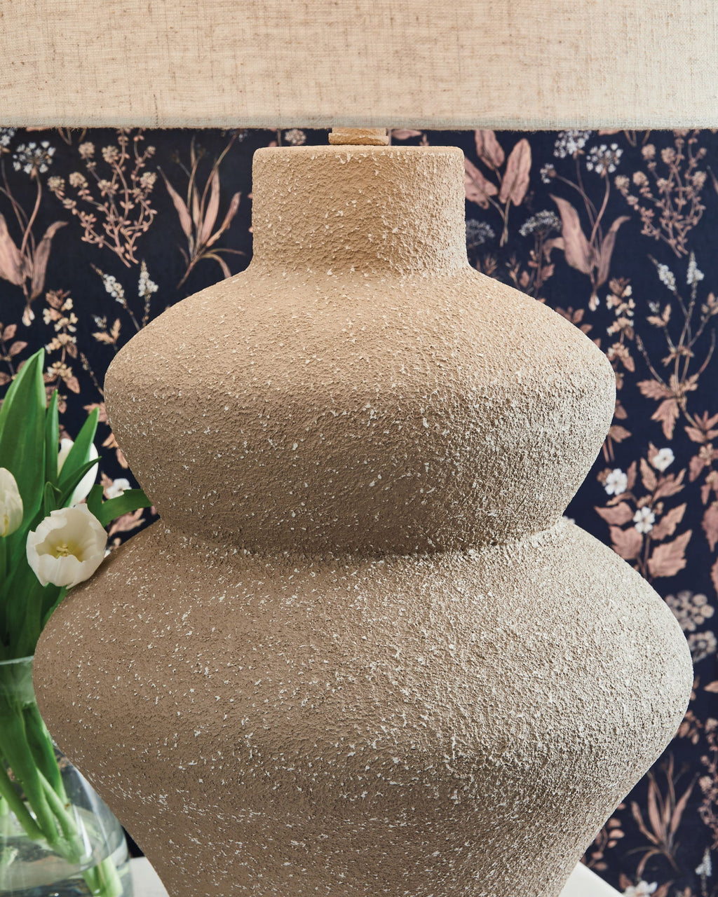 Beige textured metal table lamp base with drum fabric shade, close-up