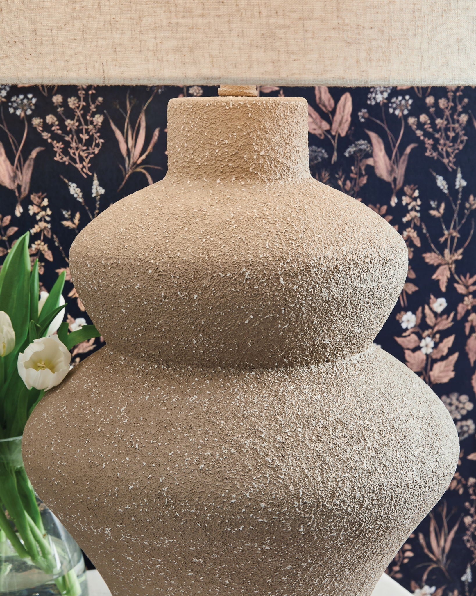 Beige textured metal table lamp base with drum fabric shade, close-up