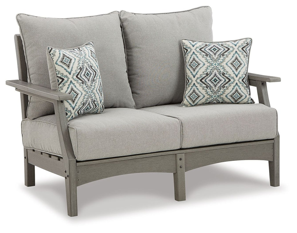 Gray upholstered loveseat with two diamond-pattern throw pillows and thick back cushions.