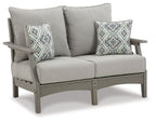 Gray upholstered loveseat with two diamond-pattern throw pillows and thick back cushions.