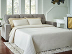 Queen sofa sleeper in gray with beige bedding extended into a bed