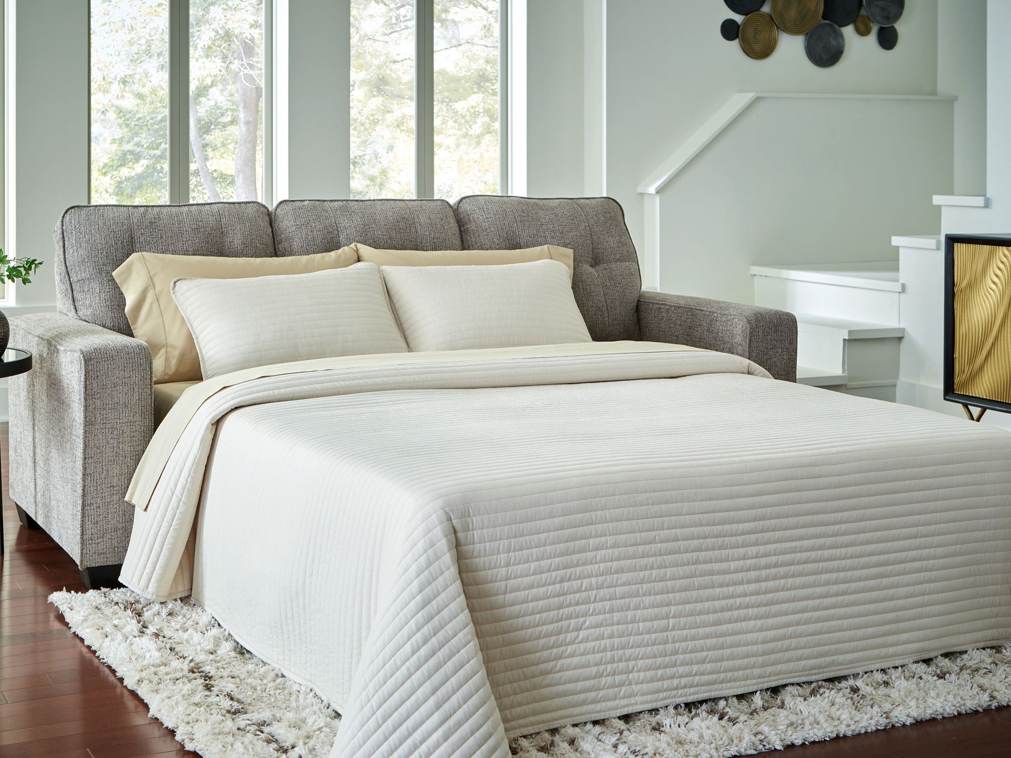 Queen sofa sleeper in gray with beige bedding extended into a bed