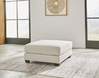Oversized ottoman in beige fabric with black feet and a square cushion top.