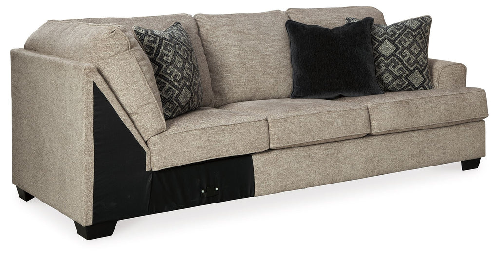 Stone-gray fabric sofa with corner wedge, tufted arms and dark patterned throw pillows