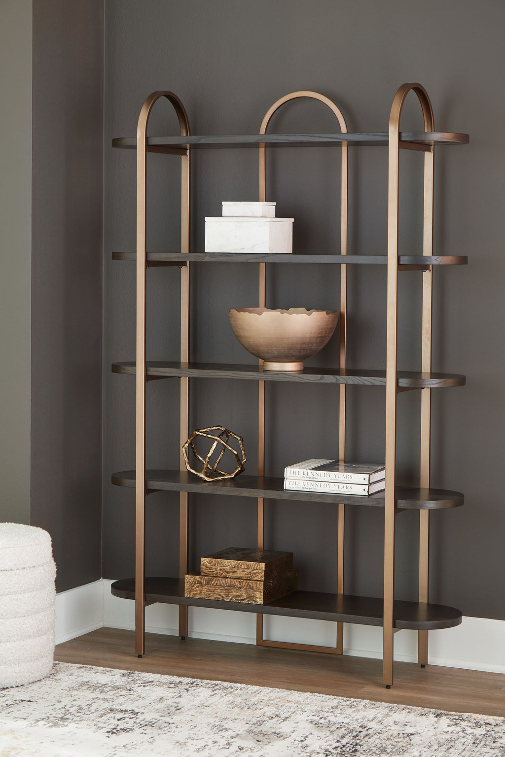 Brown bookcase with arched frame and open shelves, styled with decor on center shelf