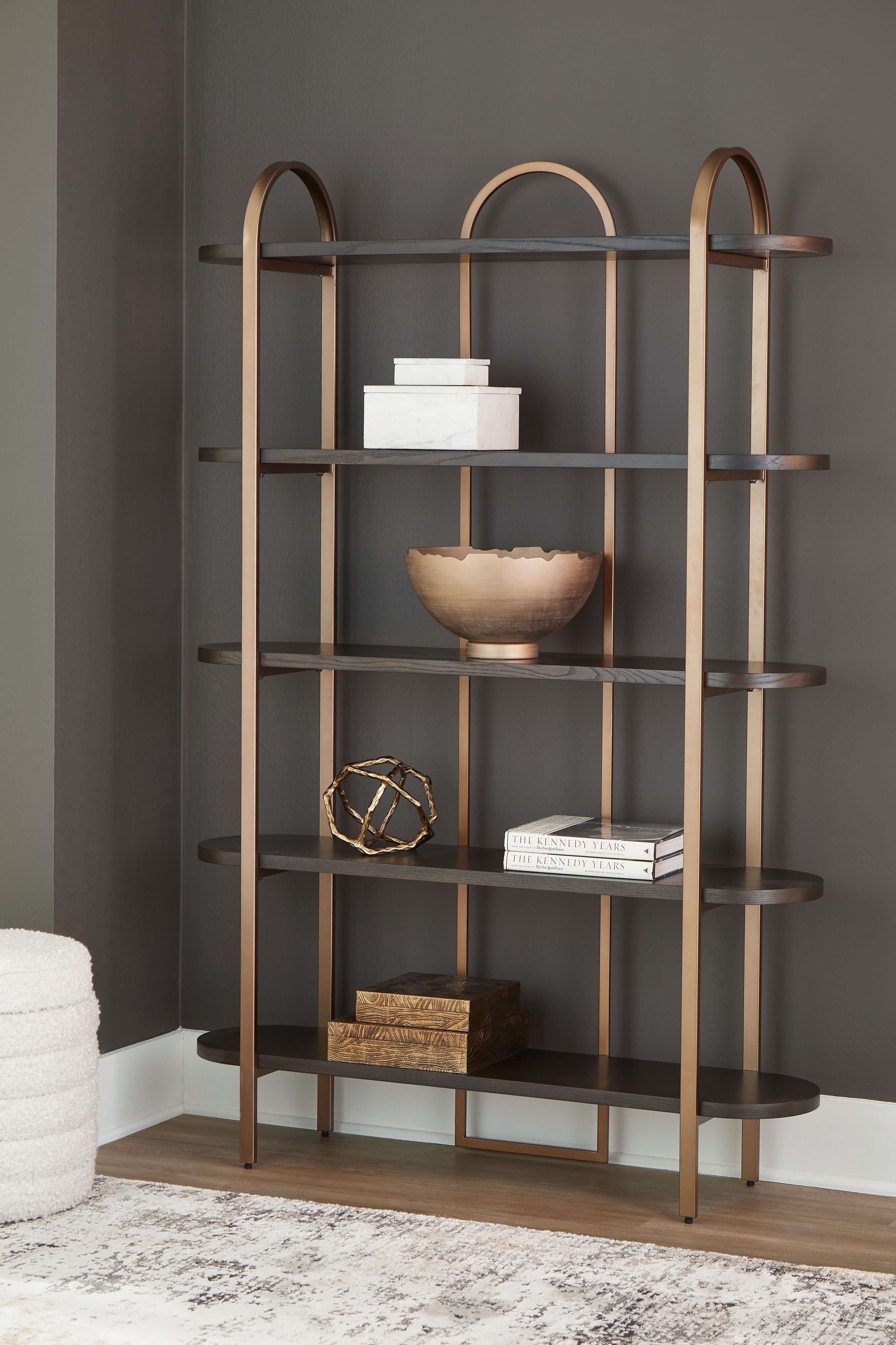 Brown bookcase with arched frame and open shelves, styled with decor on center shelf