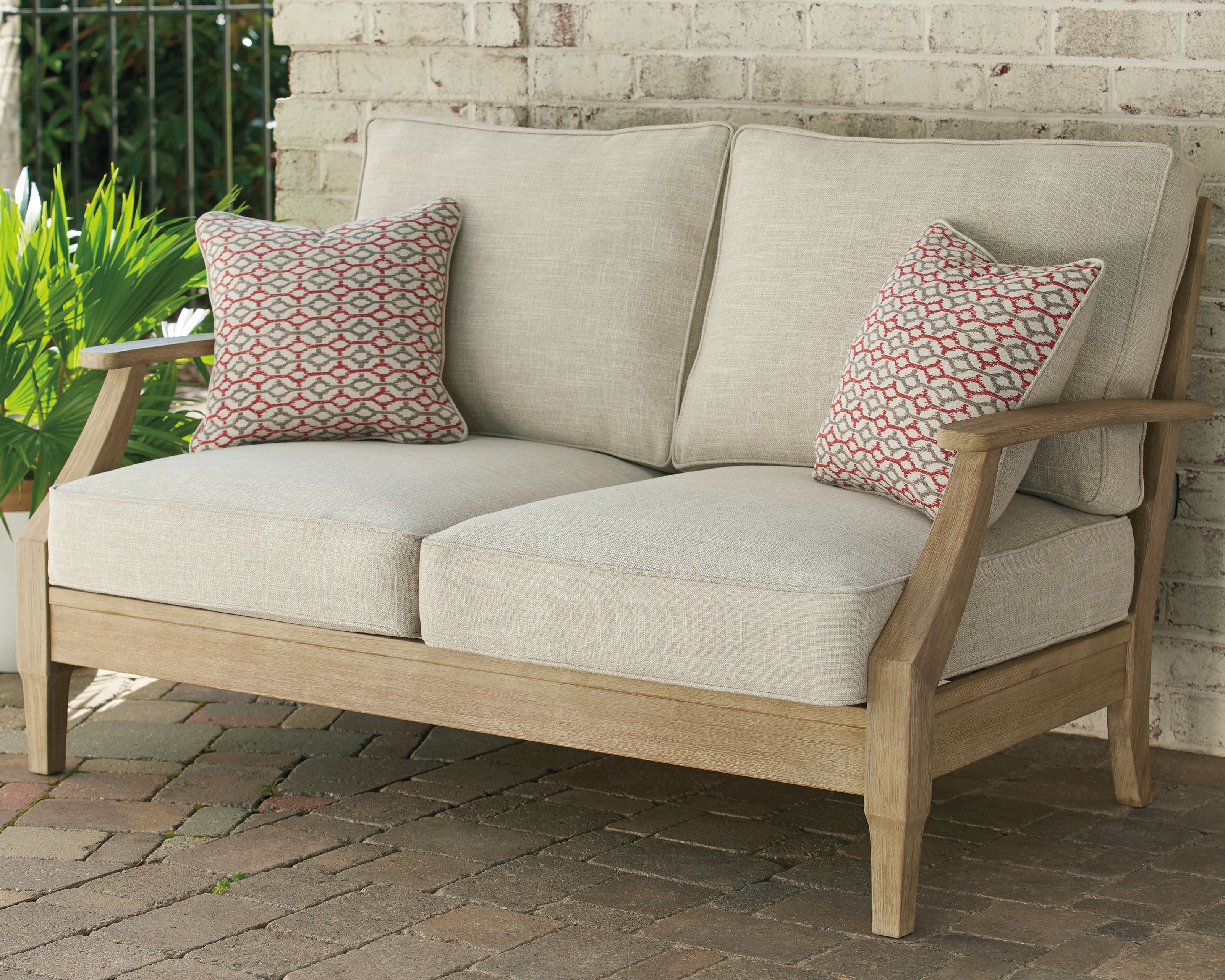 Beige loveseat with cushion, wood frame, and two patterned throw pillows