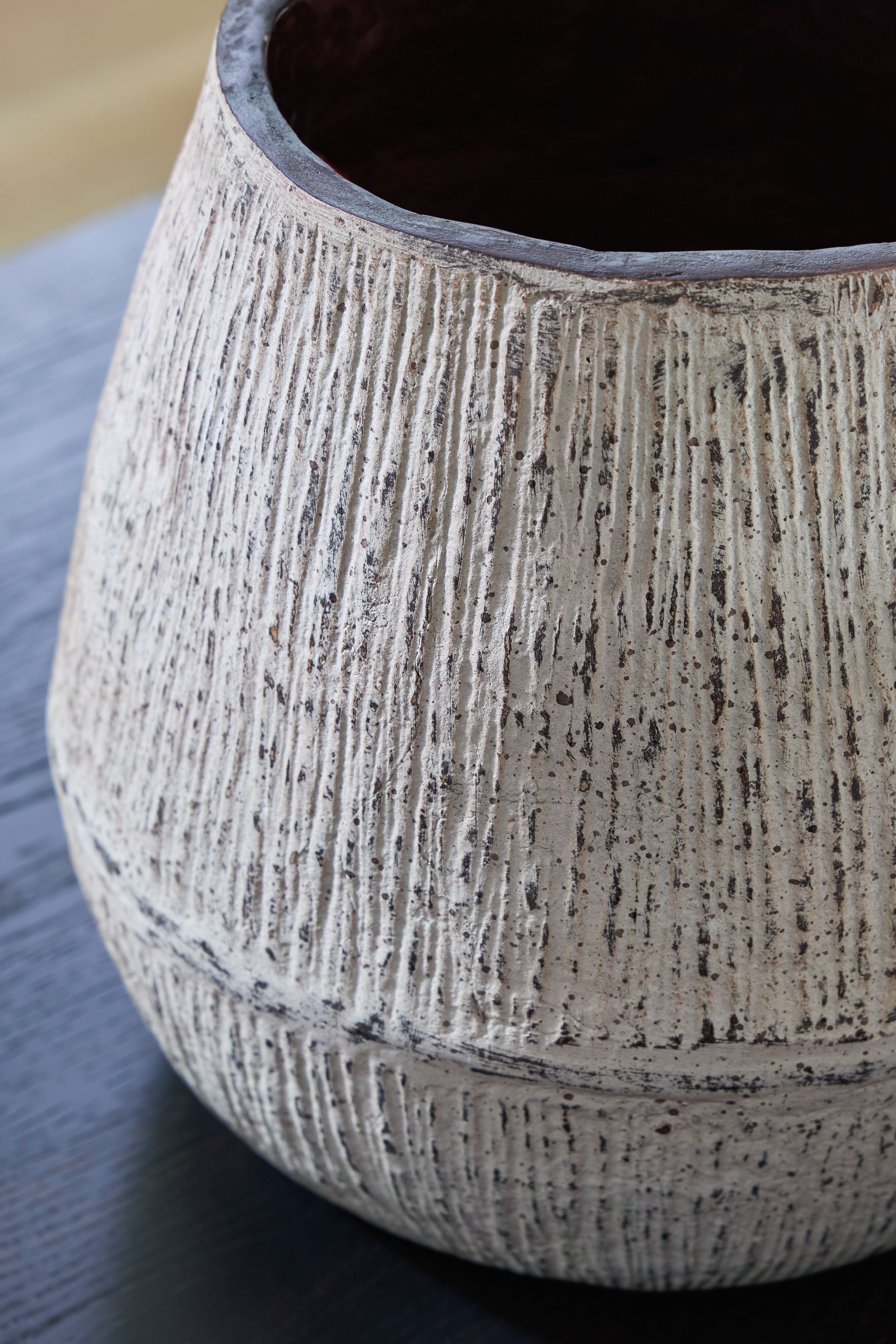Ceramic vase top edge with dark interior opening and speckled light gray textured sides