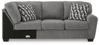 Gray fabric corner wedge sofa with three seat cushions, square arms, and patterned pillows