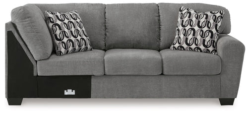 Gray fabric corner wedge sofa with three seat cushions, square arms, and patterned pillows