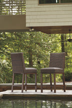 Outdoor woven barstools with dark brown frames near a stone deck