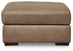 Taupe upholstered ottoman with cushioned top and side seam, black feet