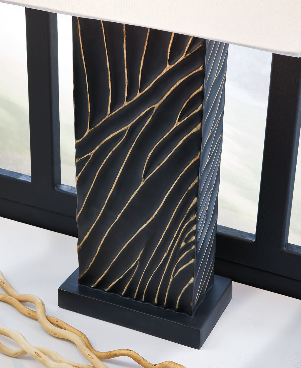 Black table lamp base with gold vein-like pattern under white fabric shade