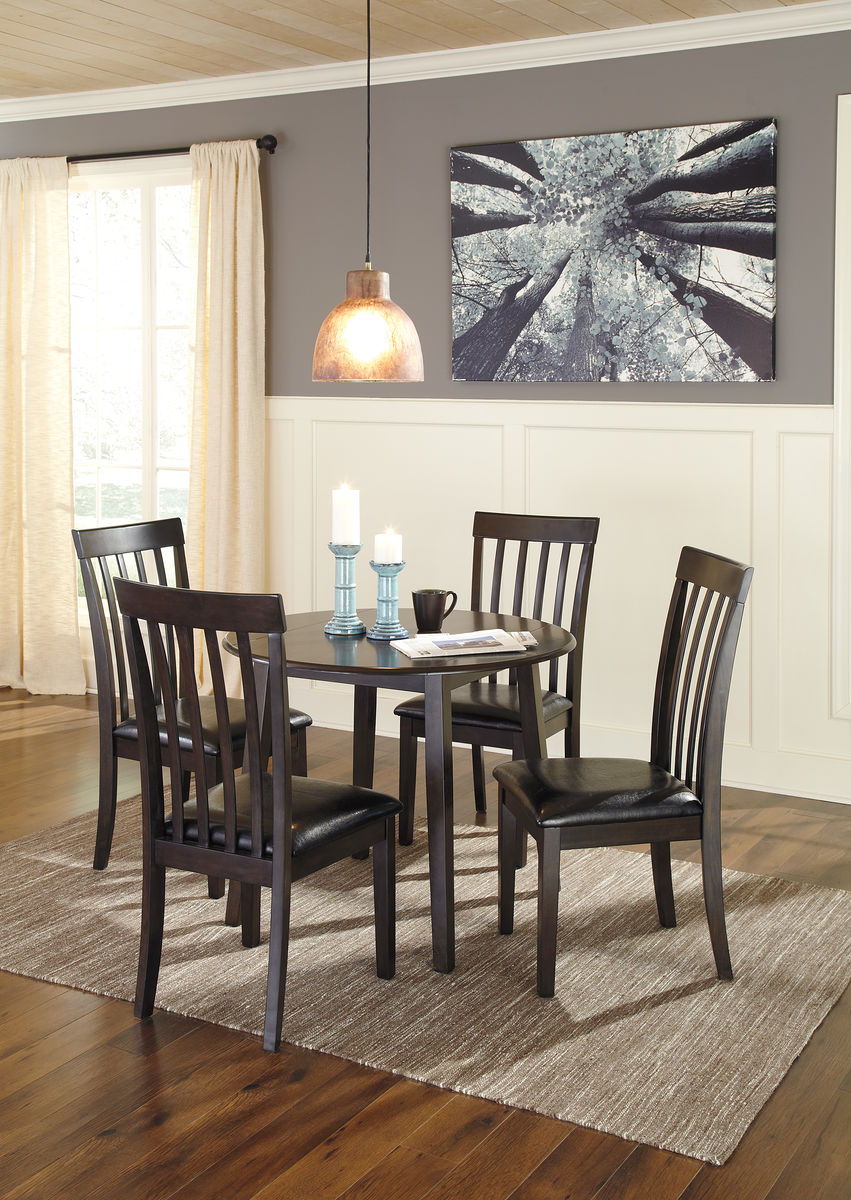 Dark brown round dining table set with four slat-back dining chairs and black cushions