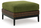 Brown wicker ottoman with green upholstered cushion
