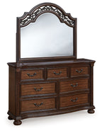 Dark brown dresser with arched mirror and carved frame, six drawers and curved feet
