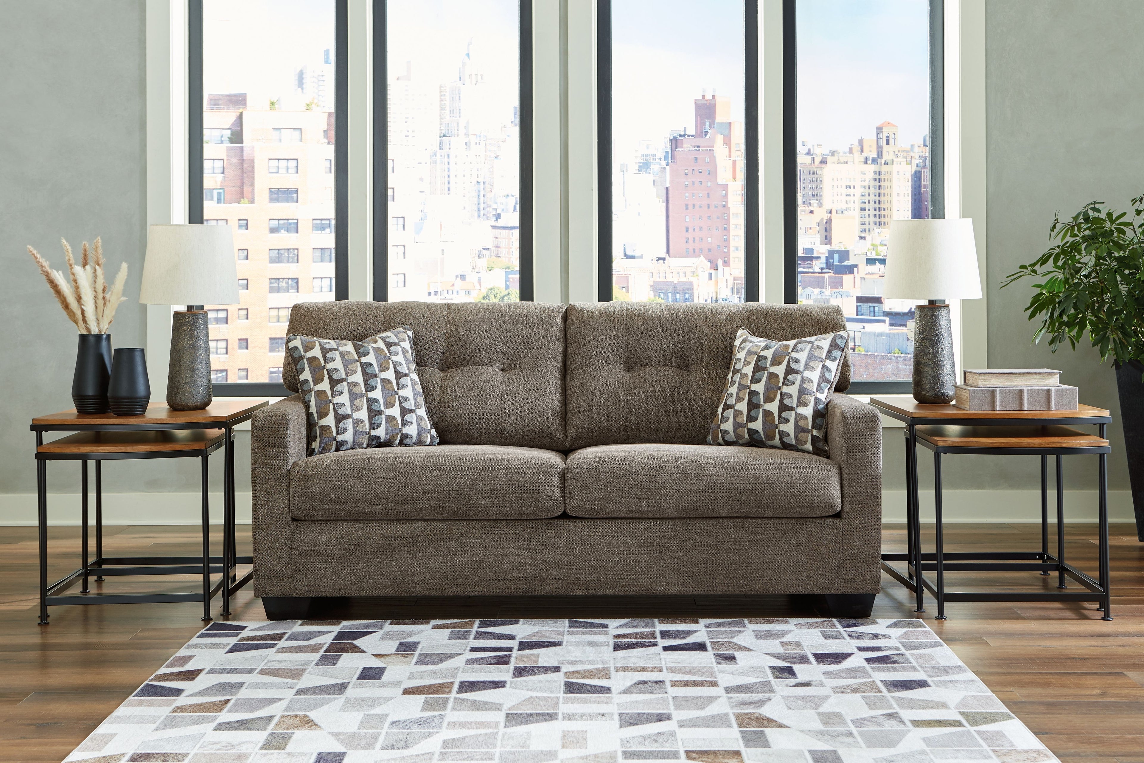 Light gray sofa with two seat cushions and two patterned throw pillows