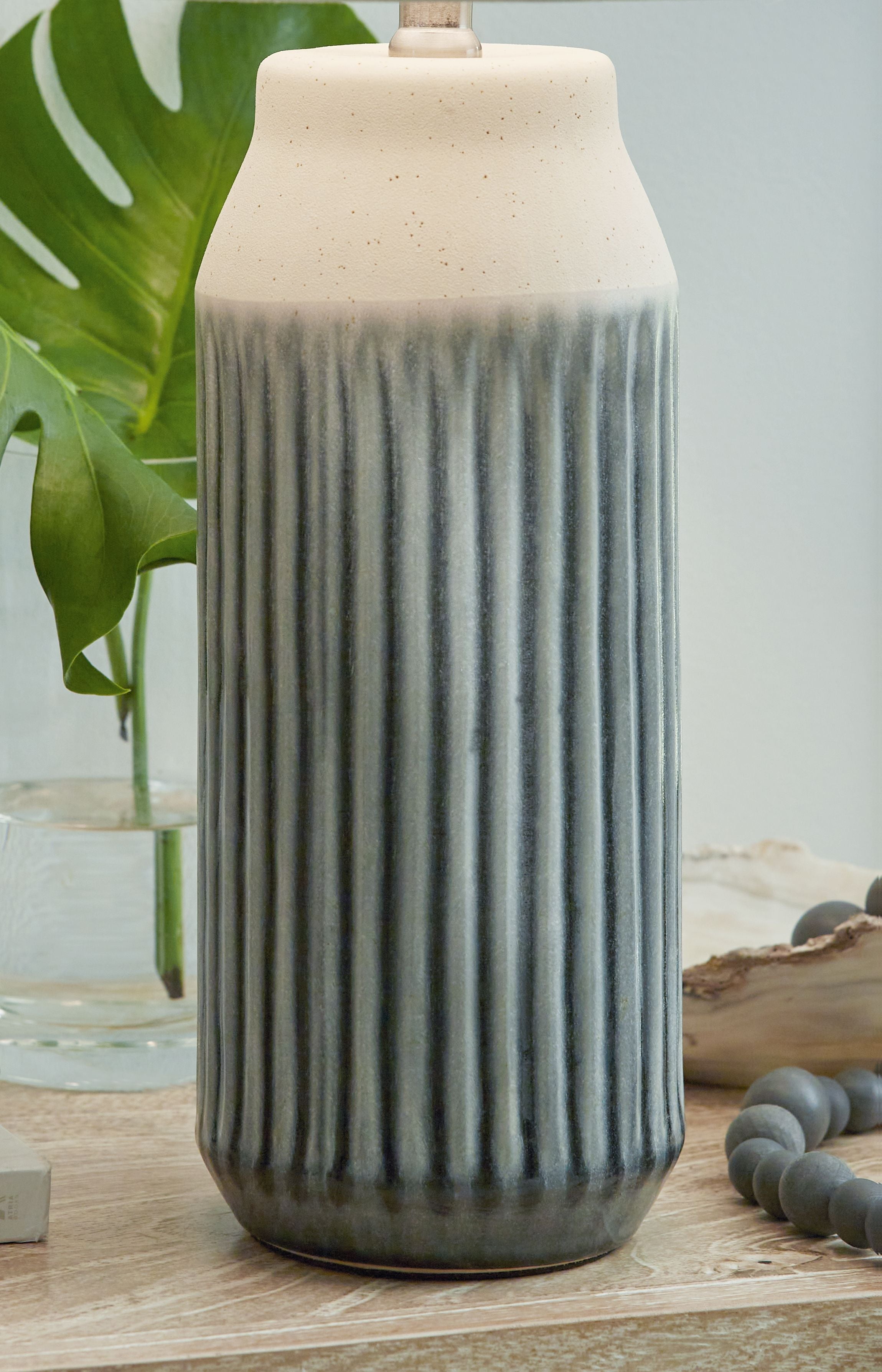 Ceramic table lamp with tall ribbed blue base and textured beige fabric shade