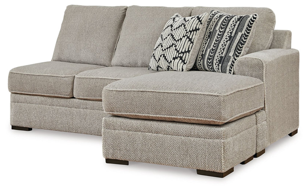 Sofa chaise with light gray fabric, two back cushions and patterned throw pillow