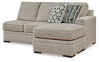 Sofa chaise with light gray fabric, two back cushions and patterned throw pillow