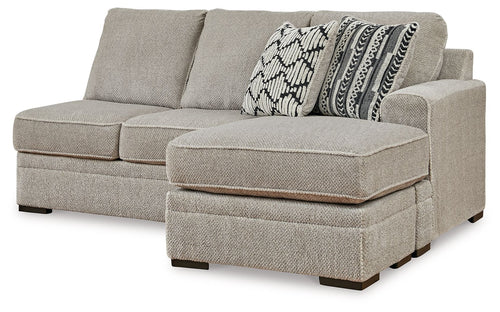 Sofa chaise with light gray fabric, two back cushions and patterned throw pillow