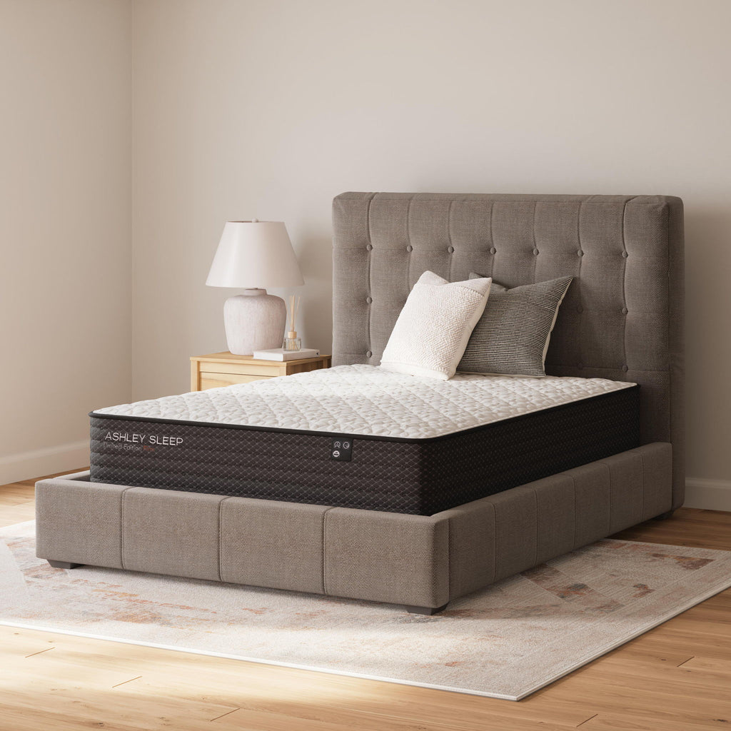 Firm mattress with white quilted top on a gray upholstered bed frame