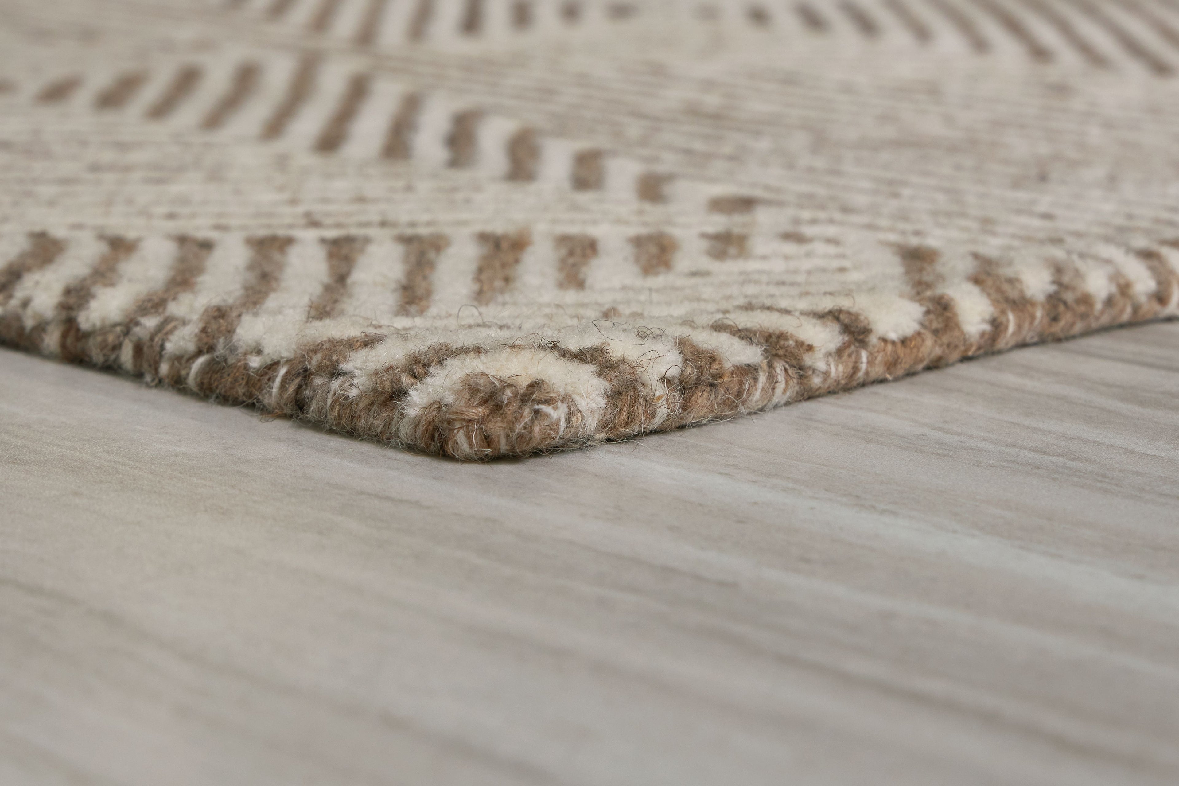 Beige rug corner with short fringe and repeating geometric pattern