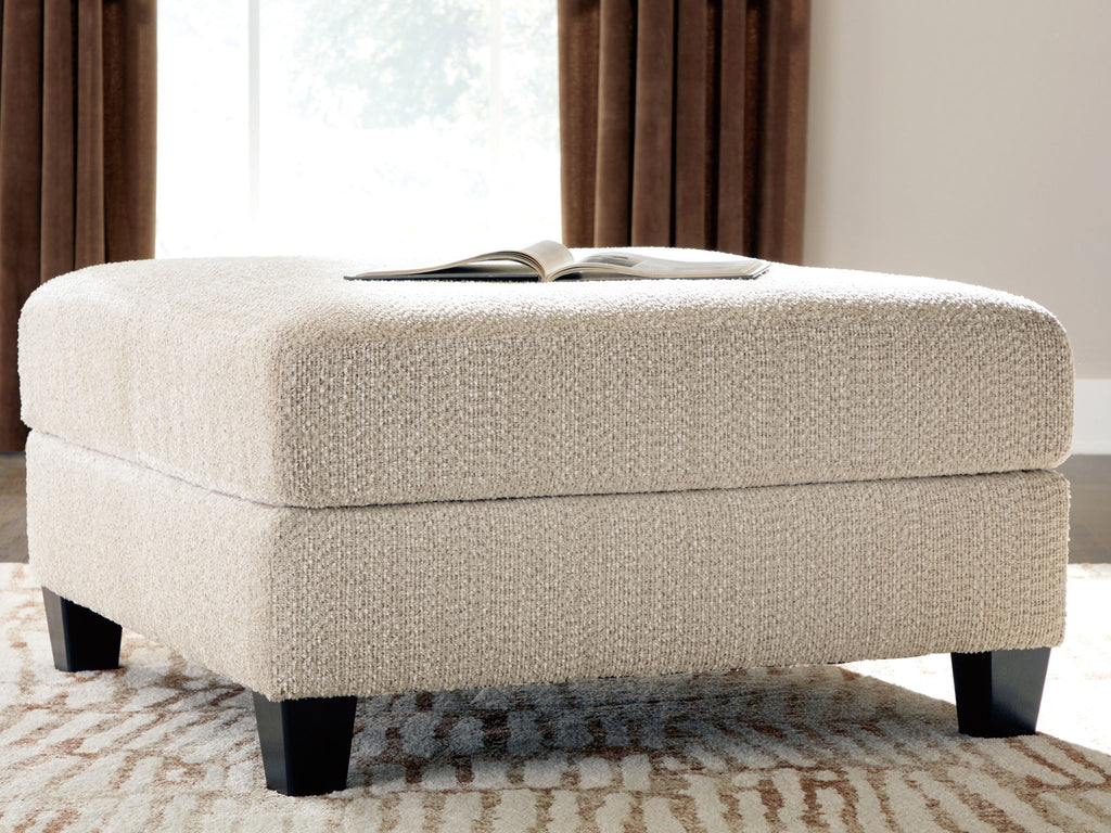Latte accent ottoman with padded rectangular top and dark wooden legs