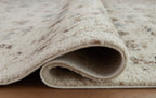 Beige area rug edge with folded pile and visible woven backing