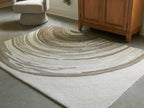 Rug in cream and dark olive with concentric wave stripes, textured low pile