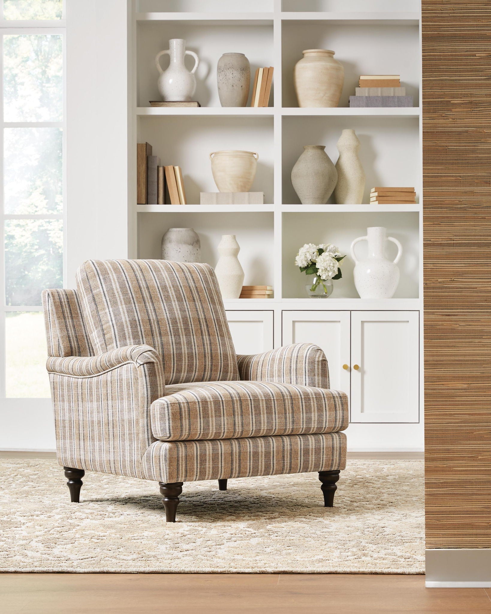 Beige striped accent chair with rolled arms and tall back cushion, dark wooden legs