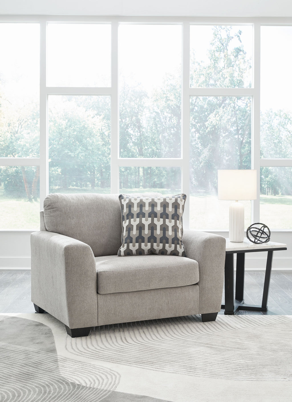 Gray flannel chair and a half with patterned back pillow on rug