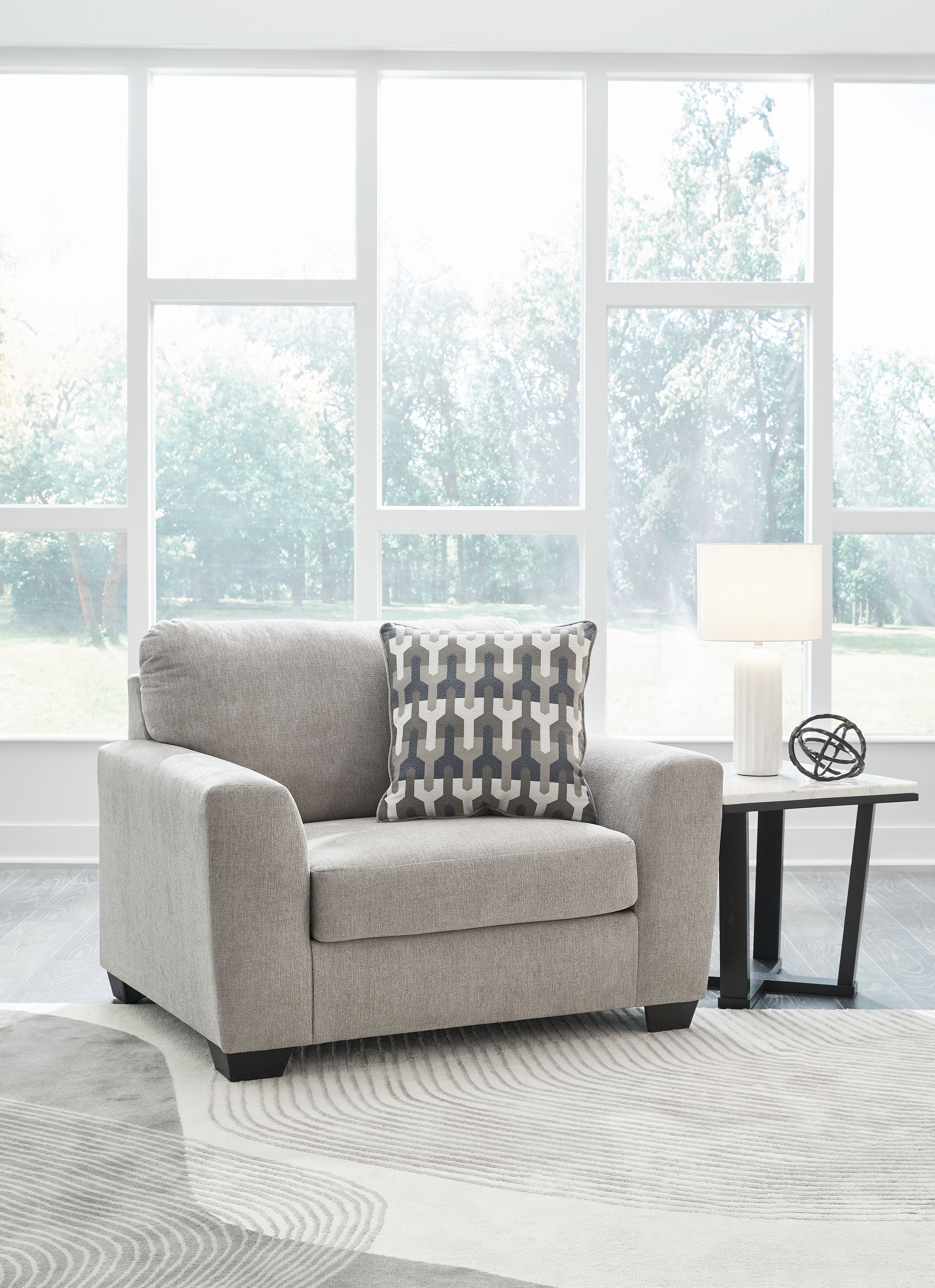 Gray flannel chair and a half with patterned back pillow on rug