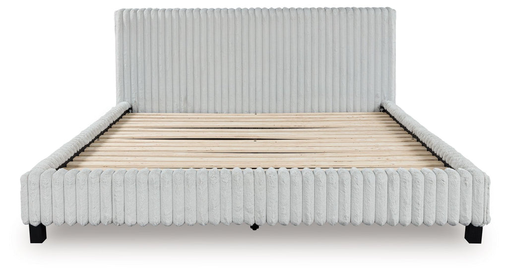 Upholstered bed with light ribbed frame and headboard, uncovered beige mattress base