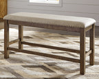 Beige upholstered bench with nailhead trim, open base frame, and dark wood legs