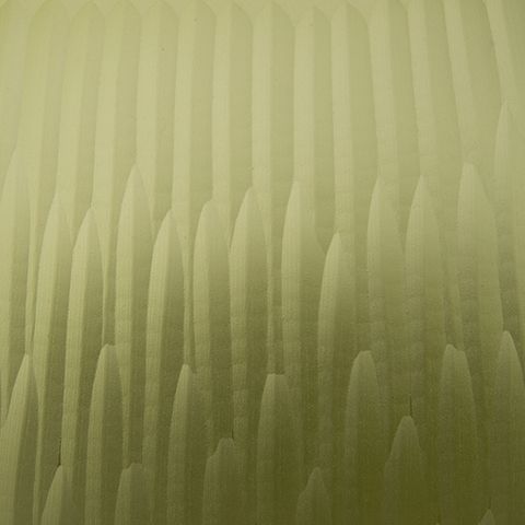 Green glass vase close-up showing vertical ridged texture across the body.