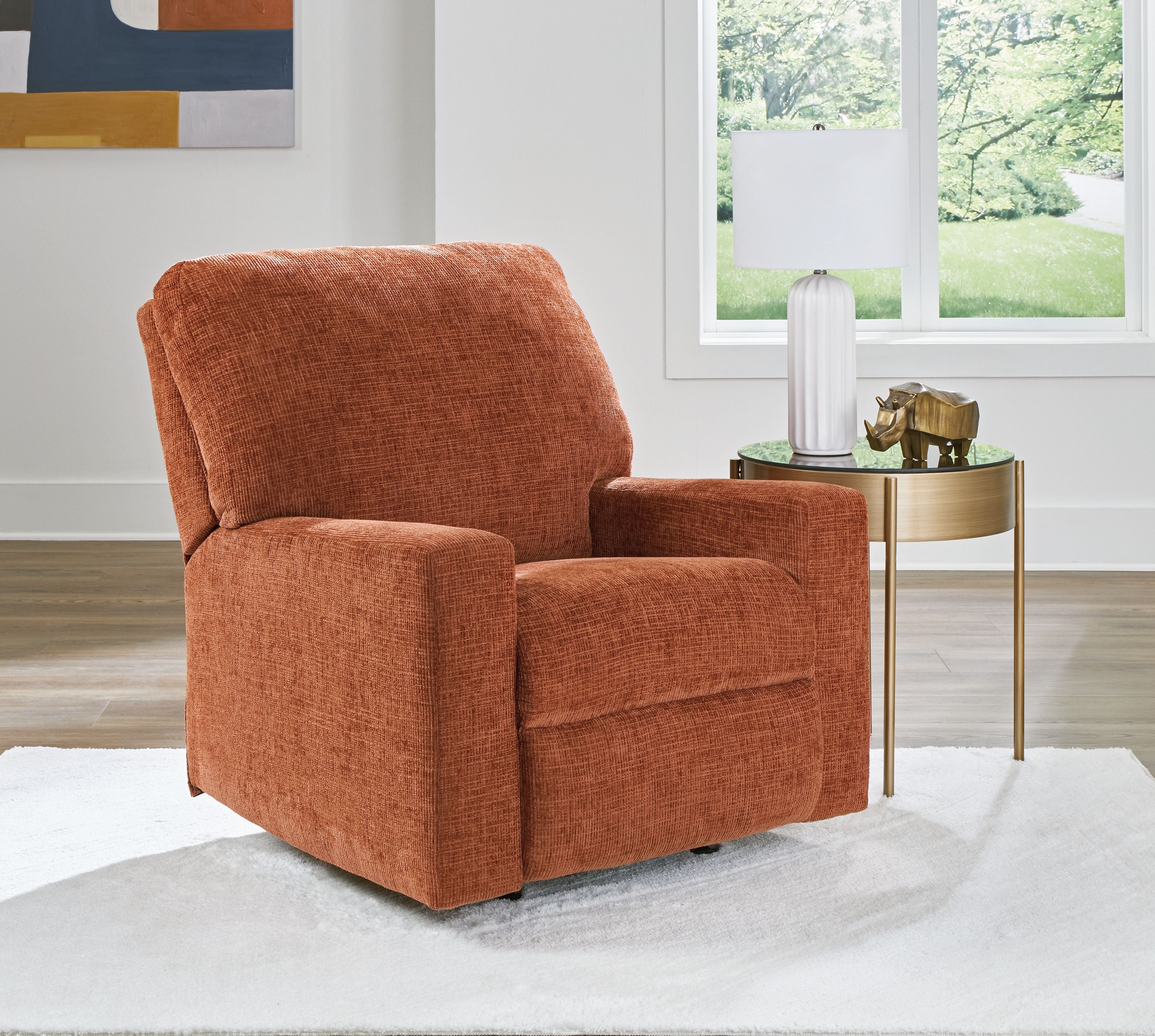 Rocker recliner chair in rust-orange upholstered fabric with curved back and arms.
