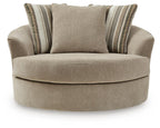 Oversized accent chair with beige upholstery and two striped pillows on the back.