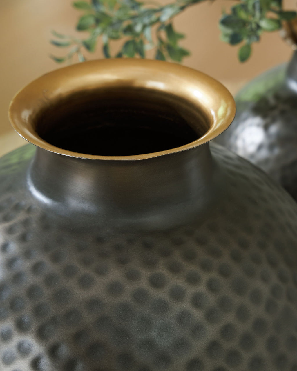 Gold-toned vase opening with dark gray hammered exterior and dimpled pattern