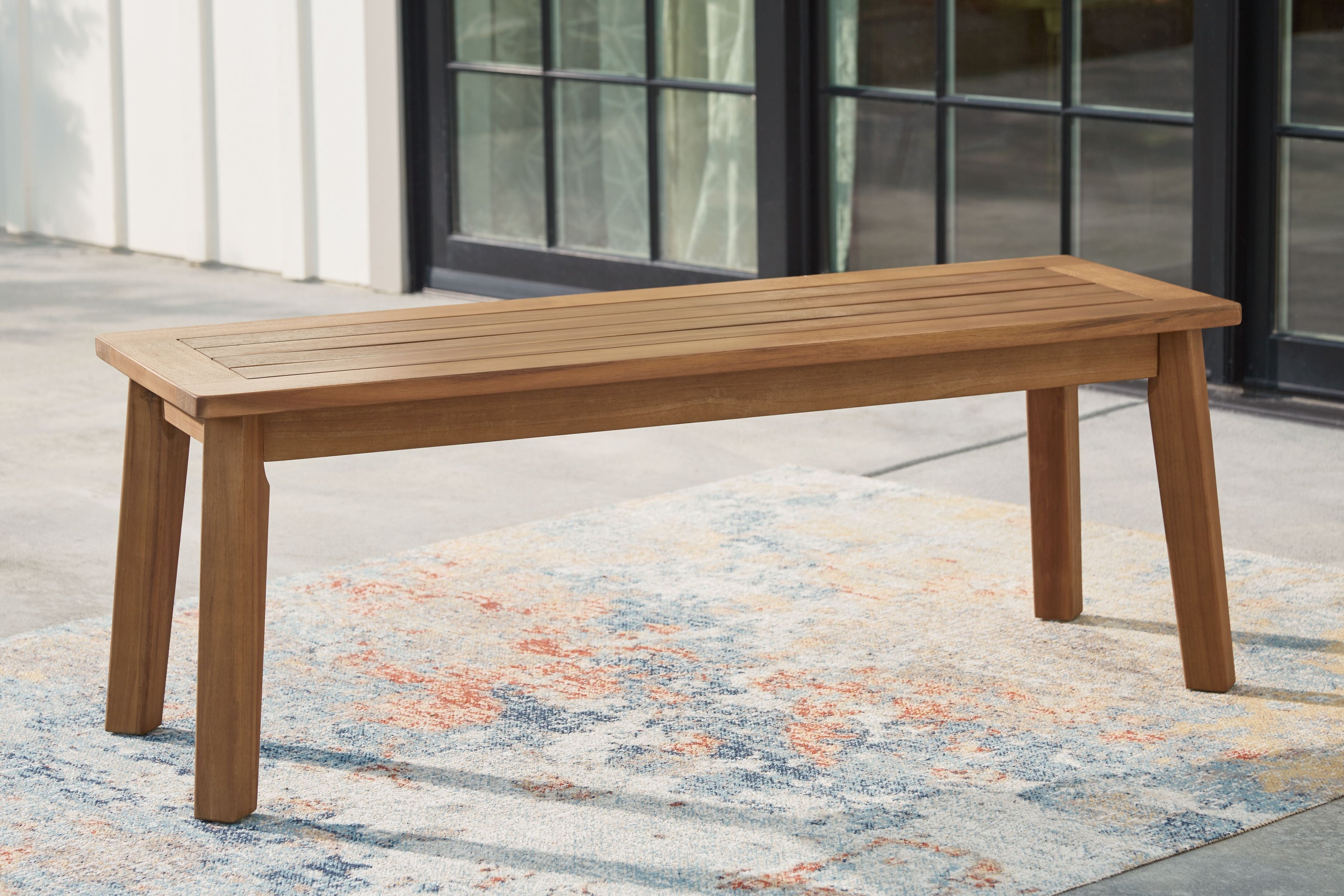 Light brown wooden bench with long slatted seat and tapered legs