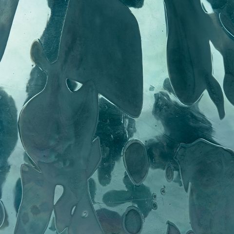 Close-up of blue glass vase surface with glossy abstract drip and puddle shapes