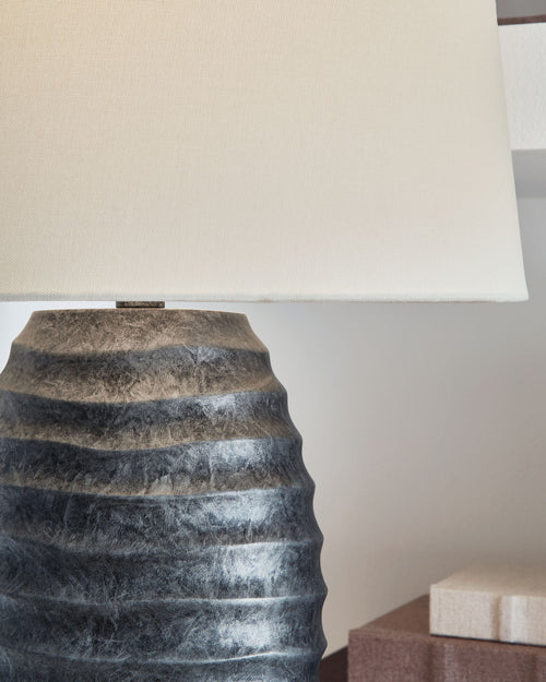 Antique silver table lamp base with sculpted ridges and beige fabric shade