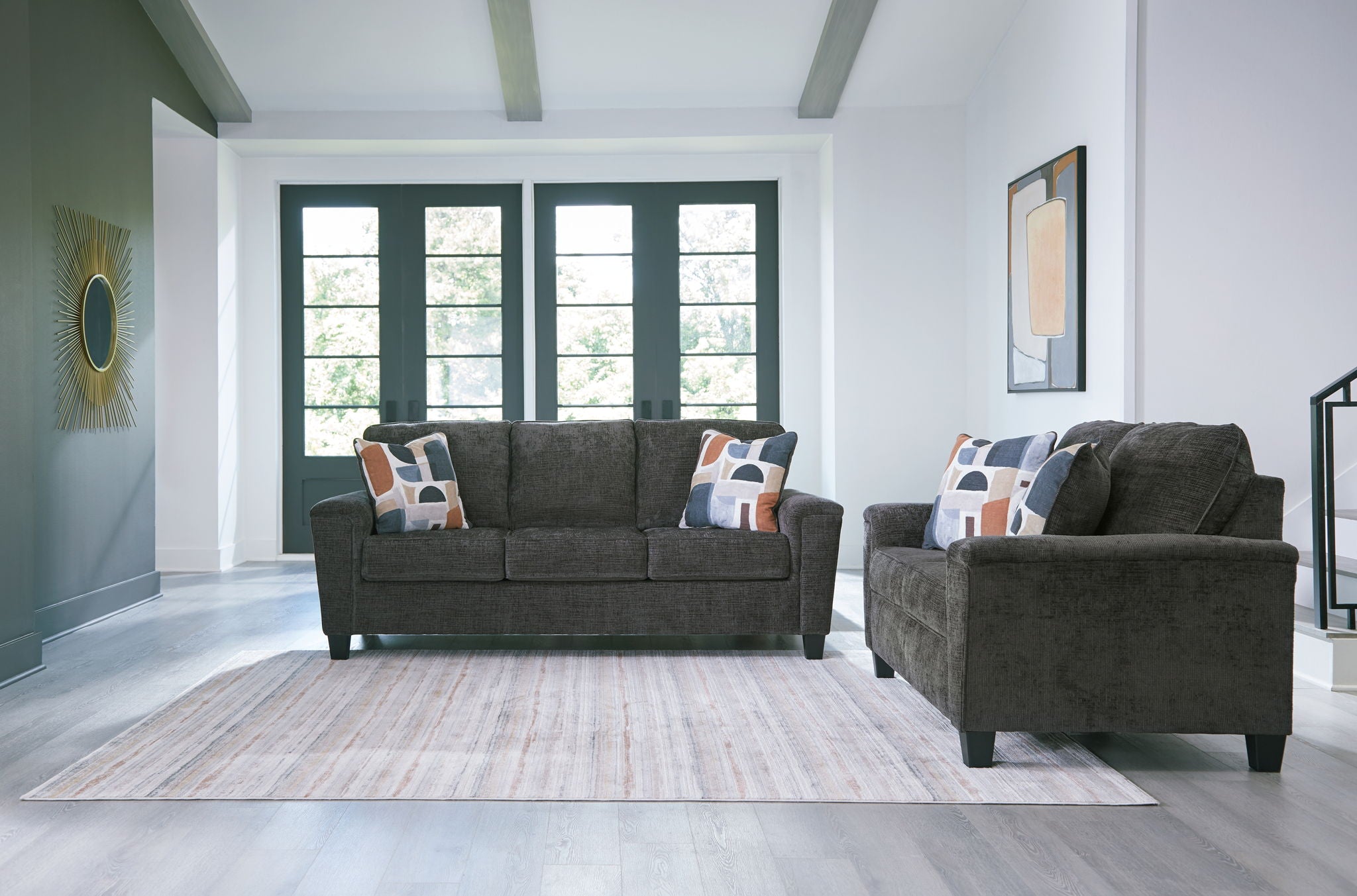 Black upholstered sofa and matching accent chair with patterned throw pillows