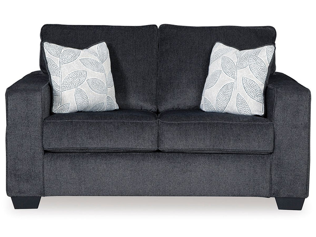 Dark gray stationary loveseat with two white patterned throw pillows and padded arms