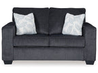 Dark gray stationary loveseat with two white patterned throw pillows and padded arms