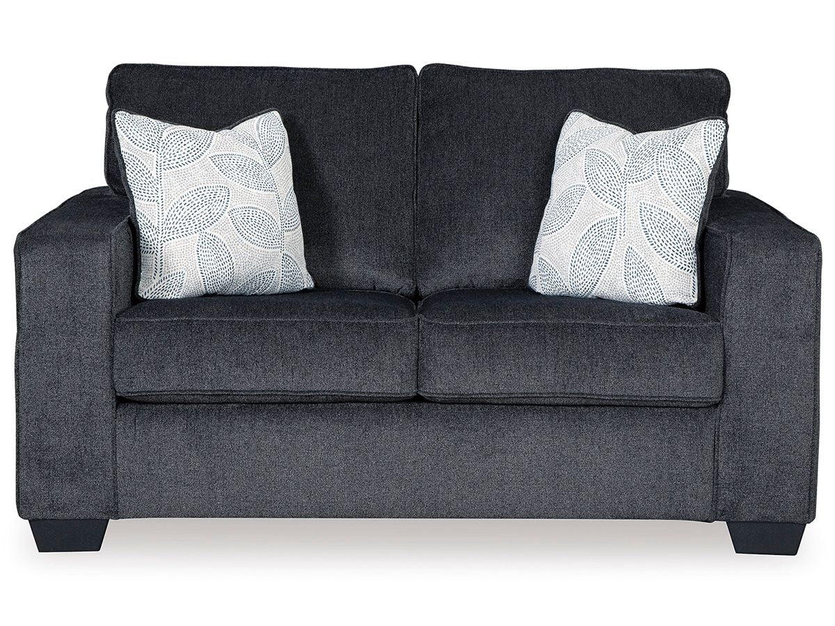 Dark gray stationary loveseat with two white patterned throw pillows and padded arms