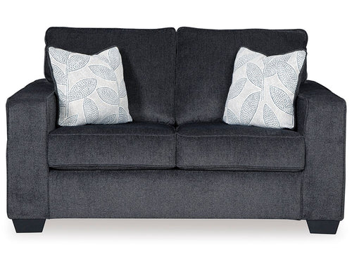 Dark gray stationary loveseat with two white patterned throw pillows and padded arms