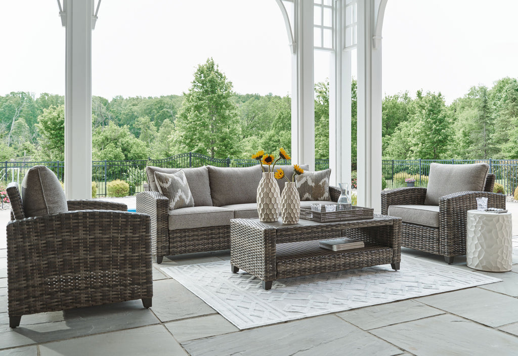 Gray wicker patio seating set with sofa, two chairs, and coffee table
