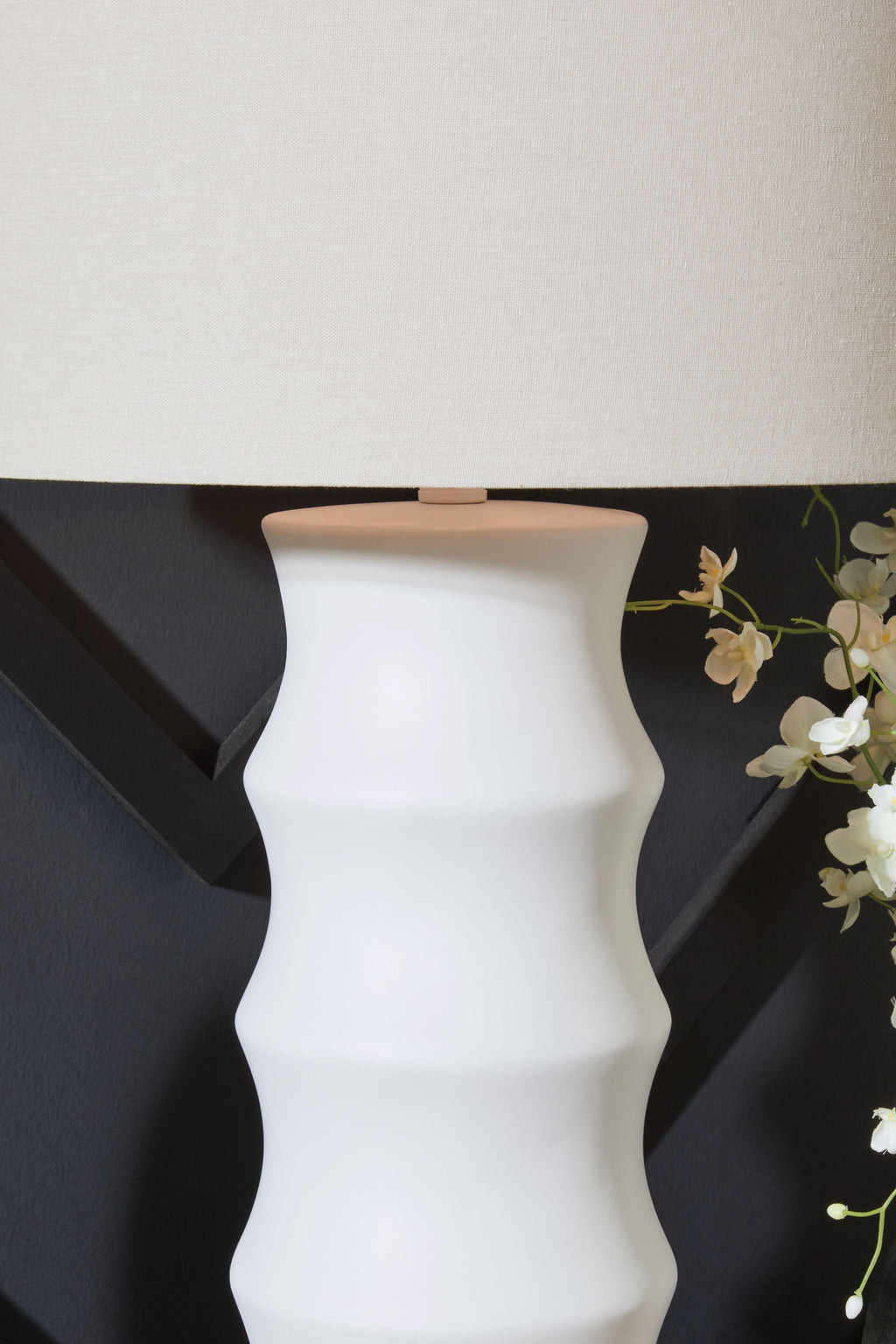 White lamp base with sculpted ridges and fabric drum shade, close-up