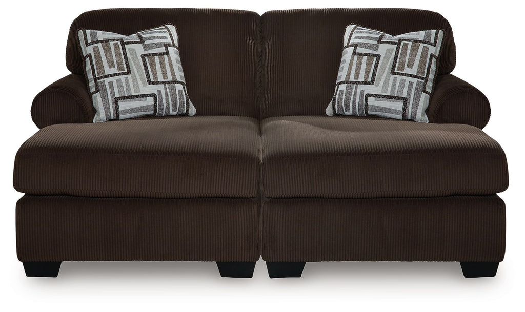 Chocolate loveseat-style sectional with two seat cushions and patterned throw pillows